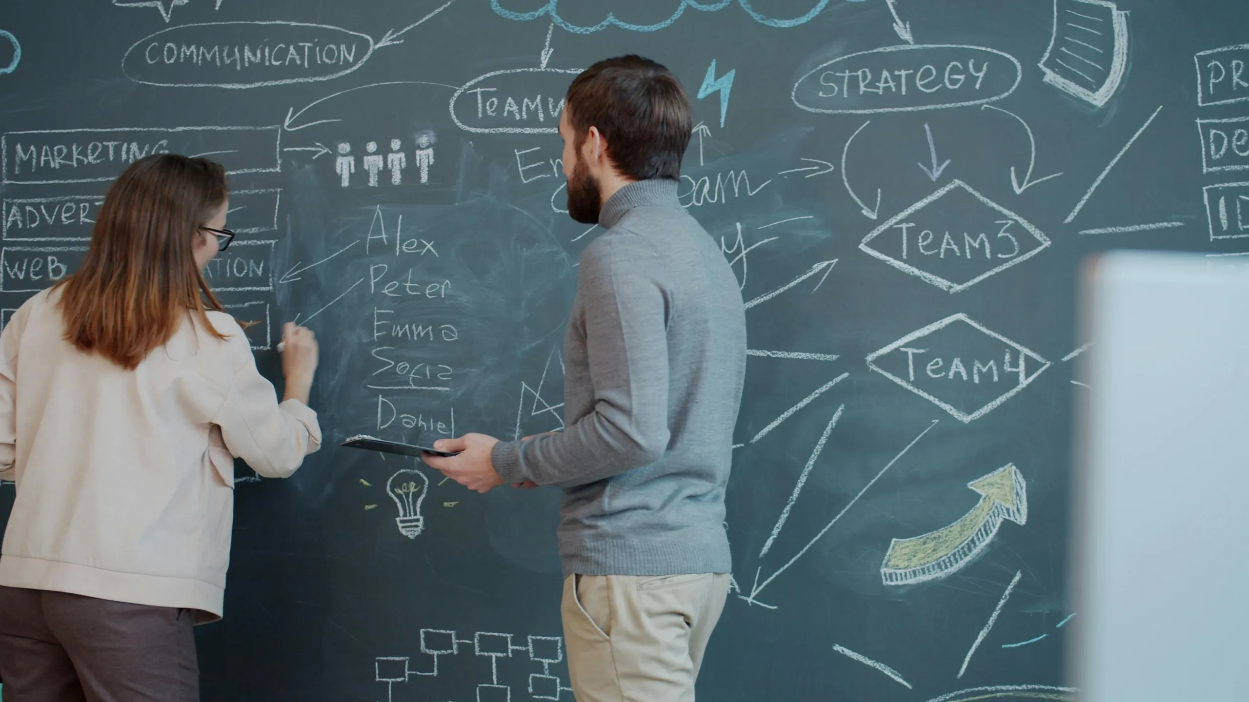 Two colleagues mapping out marketing, web and strategy ideas on a chalkboard