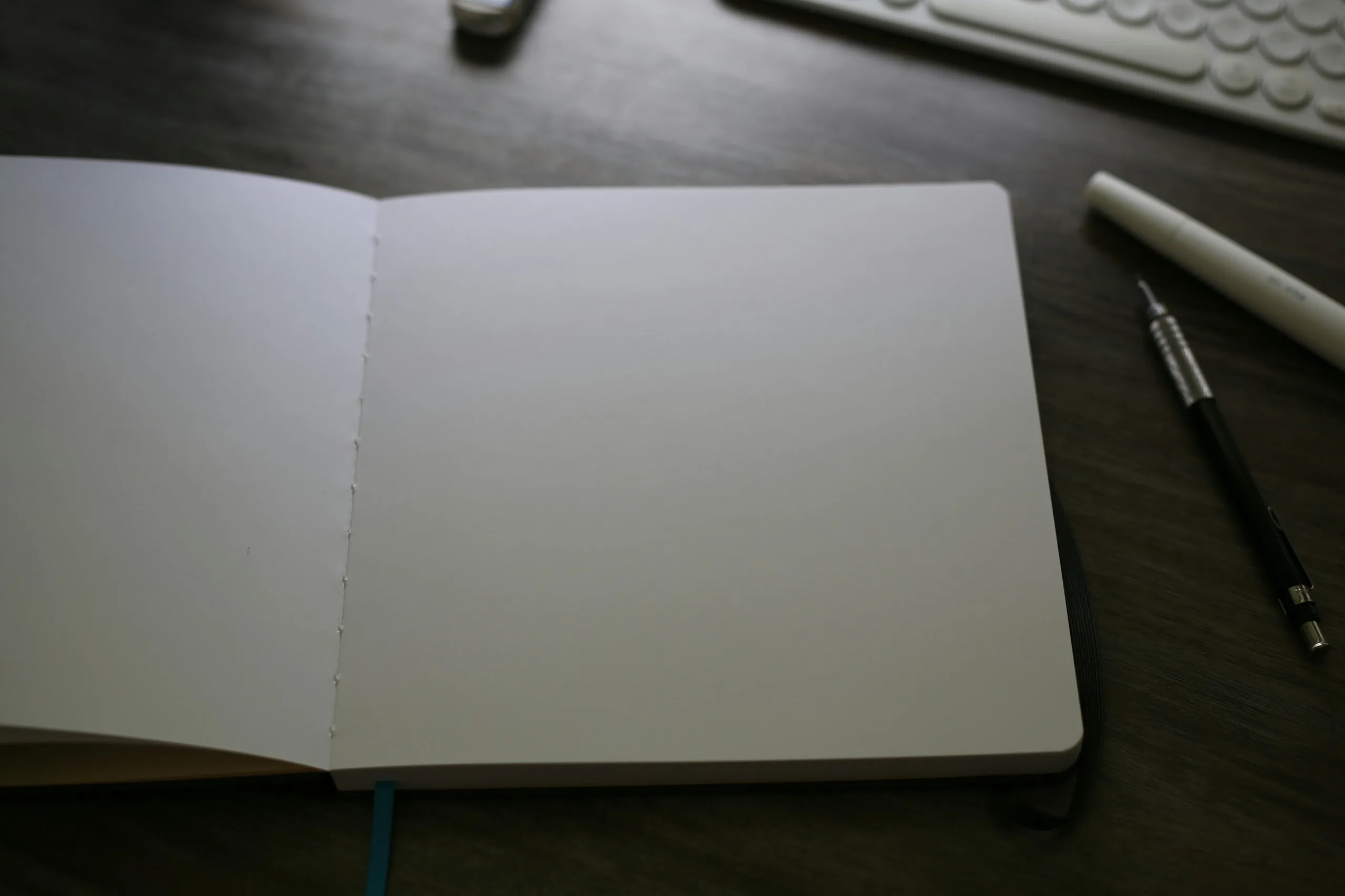An open notebook next to a keyboard on a desk, ready for planning